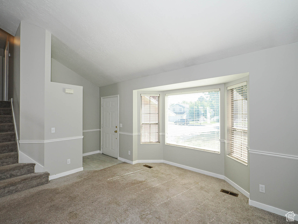 Carpeted entryway with stairs, lofted ceiling, and baseboards