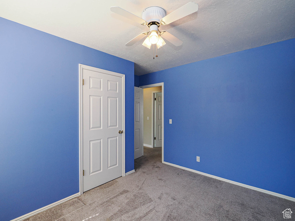 Unfurnished bedroom featuring carpet floors, baseboards, a ceiling fan, and a textured ceiling