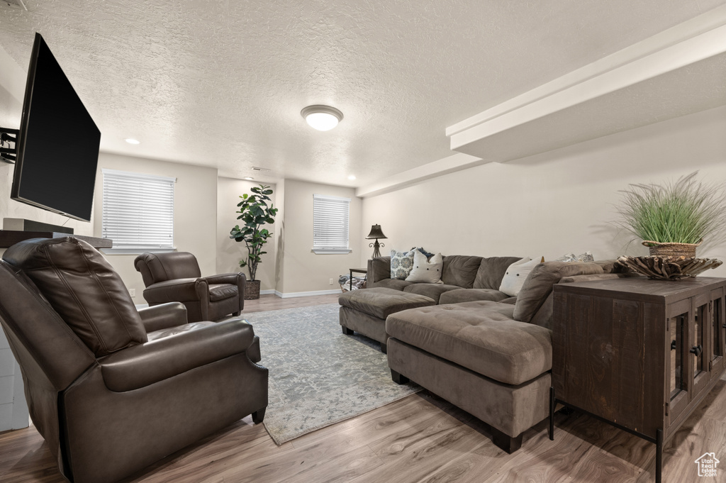 Living area with a textured ceiling, light wood-style floors, and baseboards