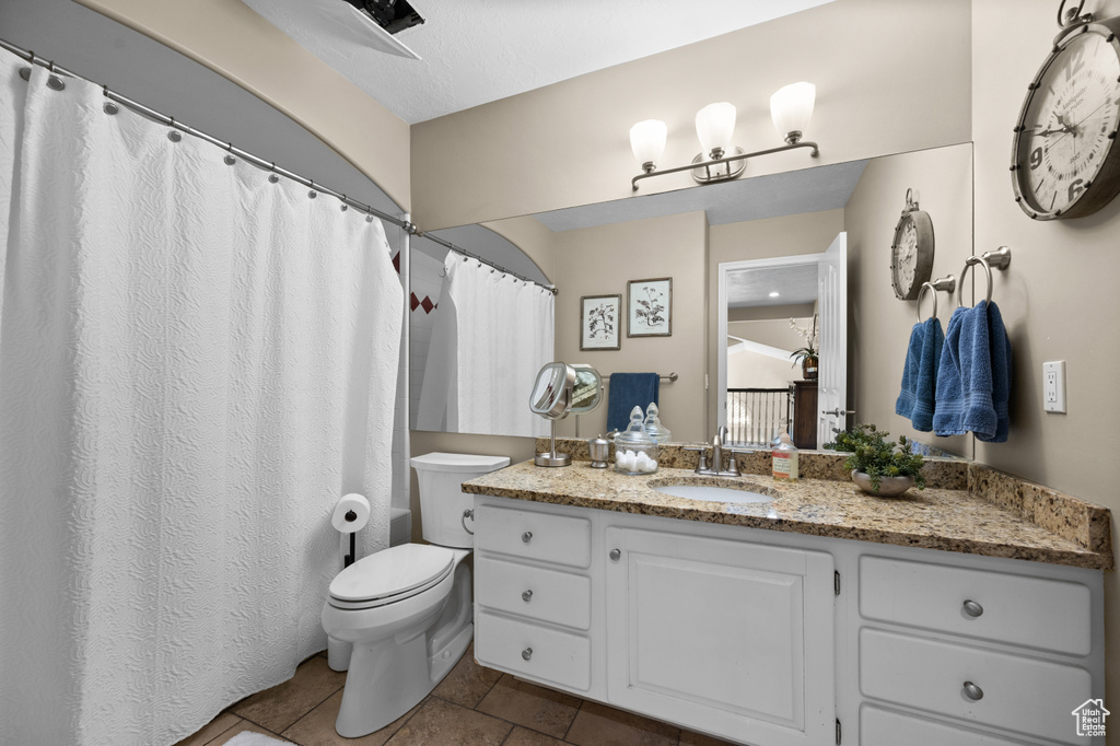 Bathroom featuring toilet, tile patterned flooring, and vanity
