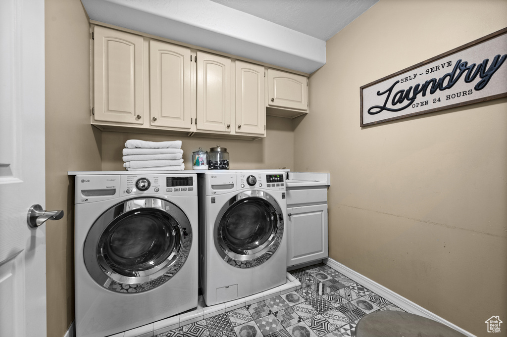 Washroom featuring cabinet space, separate washer and dryer, baseboards, and tile patterned floors
