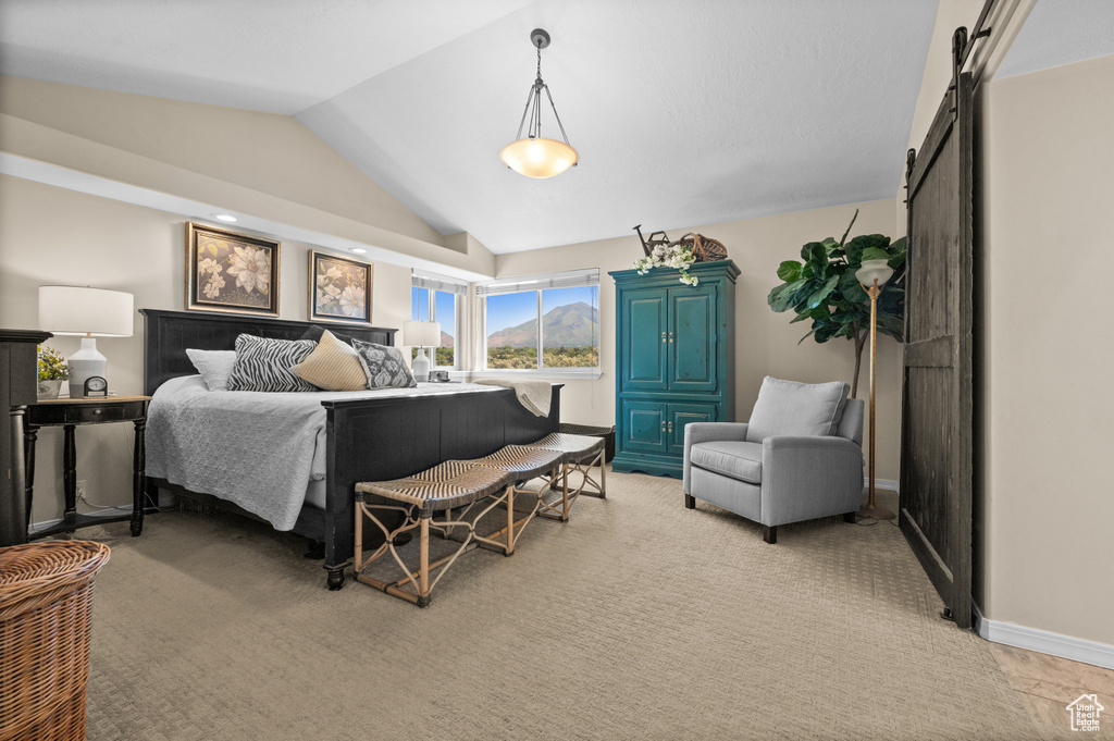 Bedroom with a barn door, vaulted ceiling, and baseboards