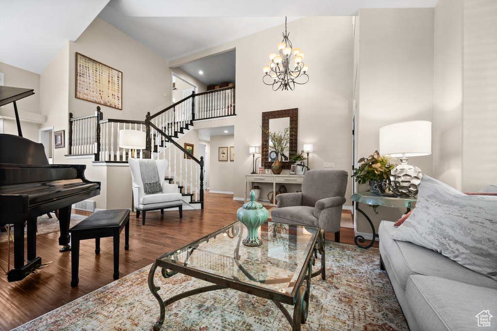 Living room featuring wood finished floors, a chandelier, baseboards, stairway, and a high ceiling