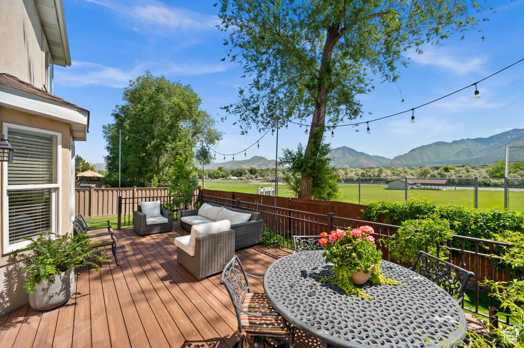 Wooden deck with a mountain view, an outdoor hangout area, a fenced backyard, and outdoor dining space