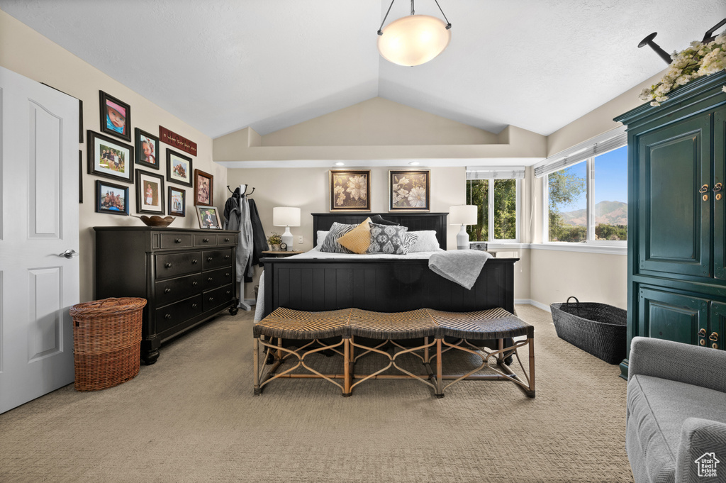 Bedroom with light carpet and lofted ceiling