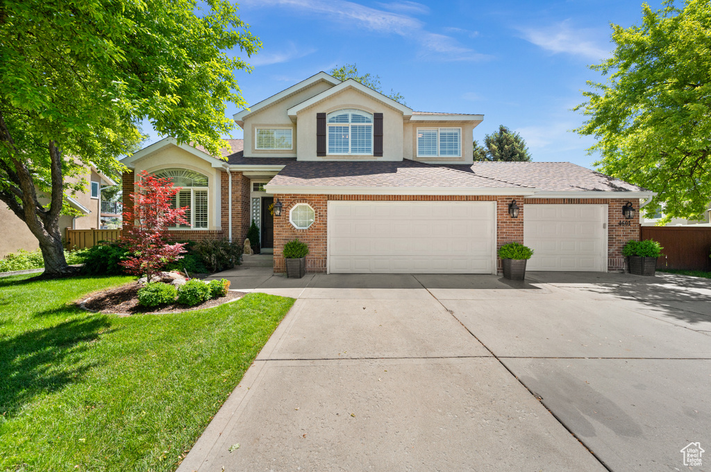Traditional home with driveway, brick siding, stucco siding, and a shingled roof