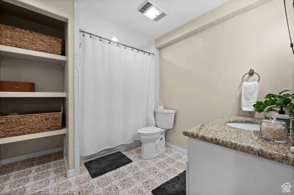 Bathroom with vanity, toilet, baseboards, shower / tub combo with curtain, and tile patterned flooring