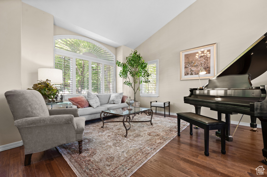 Living room with baseboards, wood finished floors, and high vaulted ceiling