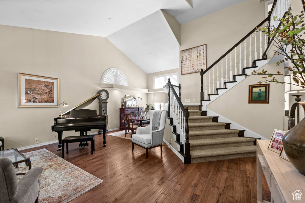 Foyer entrance with stairway, high vaulted ceiling, dark wood-style flooring, and baseboards