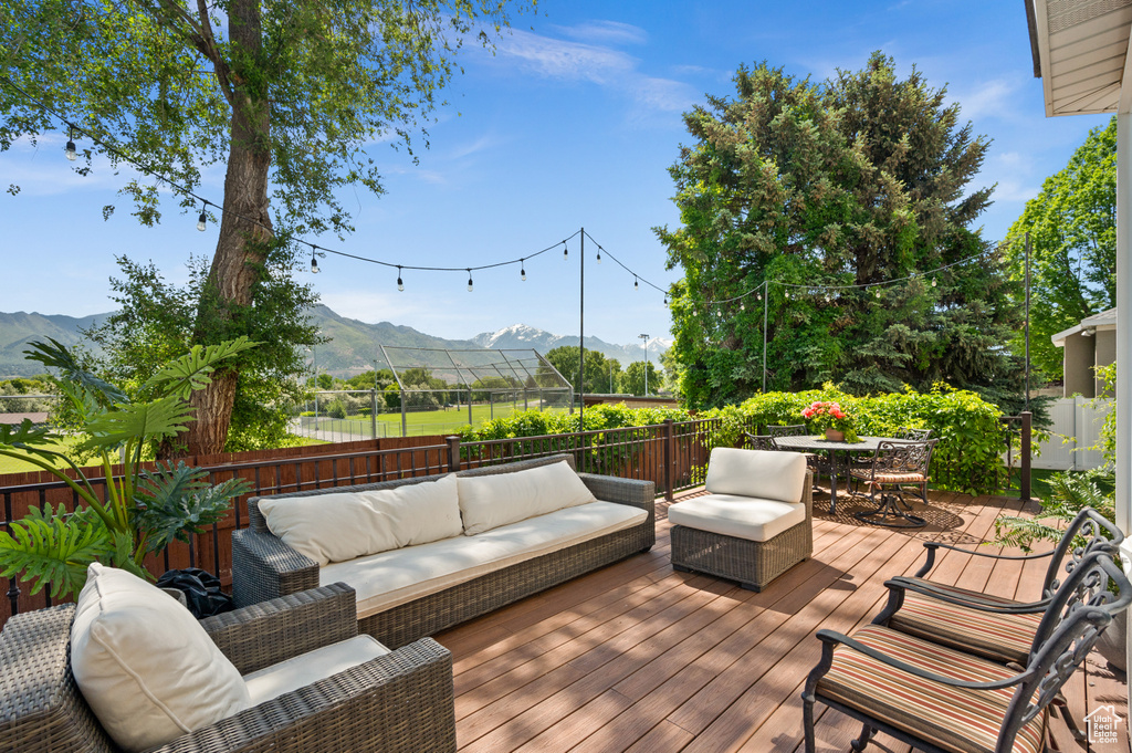 Deck with a mountain view, an outdoor living space, outdoor dining area, and a fenced backyard