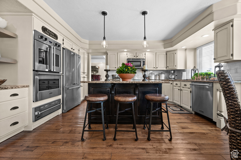 Kitchen featuring appliances with stainless steel finishes, a warming drawer, light stone counters, and a kitchen island