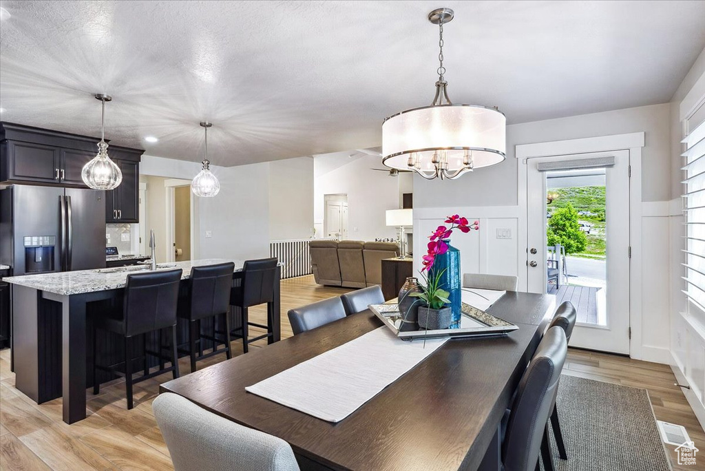 Dining space with light wood finished floors and a chandelier