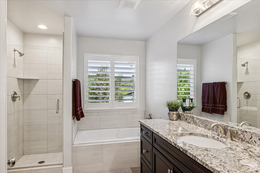 Full bath featuring a stall shower, vanity, and a garden tub