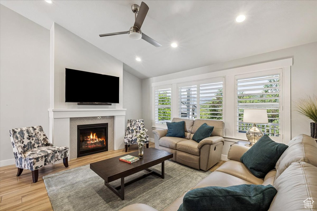 Living area with light wood finished floors, vaulted ceiling, recessed lighting, a glass covered fireplace, and a ceiling fan