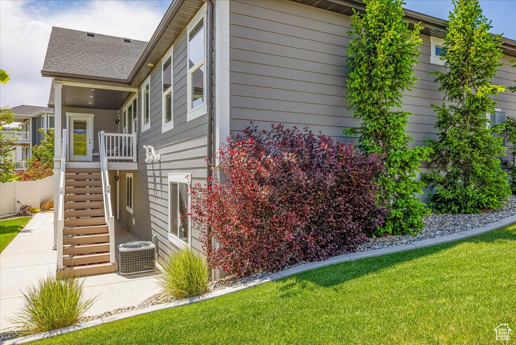 Rear view of house featuring a lawn and central AC unit