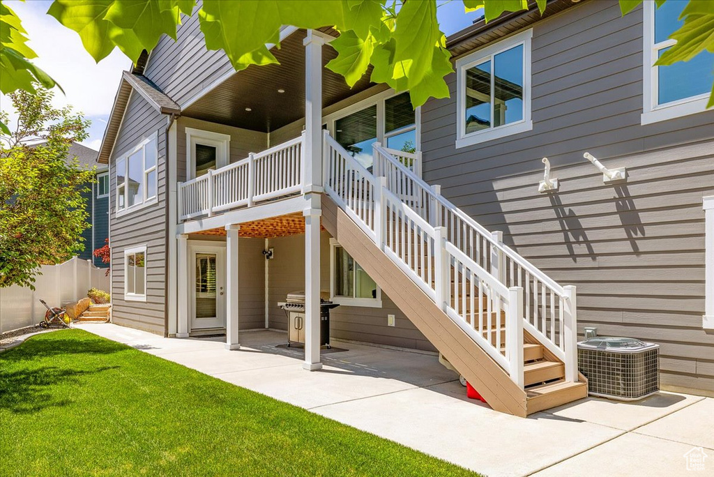 Rear view of house with central AC, stairway, a lawn, and a patio area