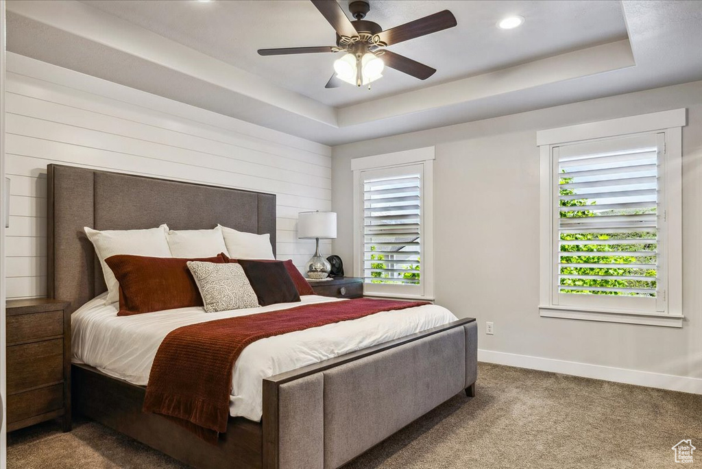 Bedroom featuring baseboards, carpet floors, a raised ceiling, recessed lighting, and a ceiling fan