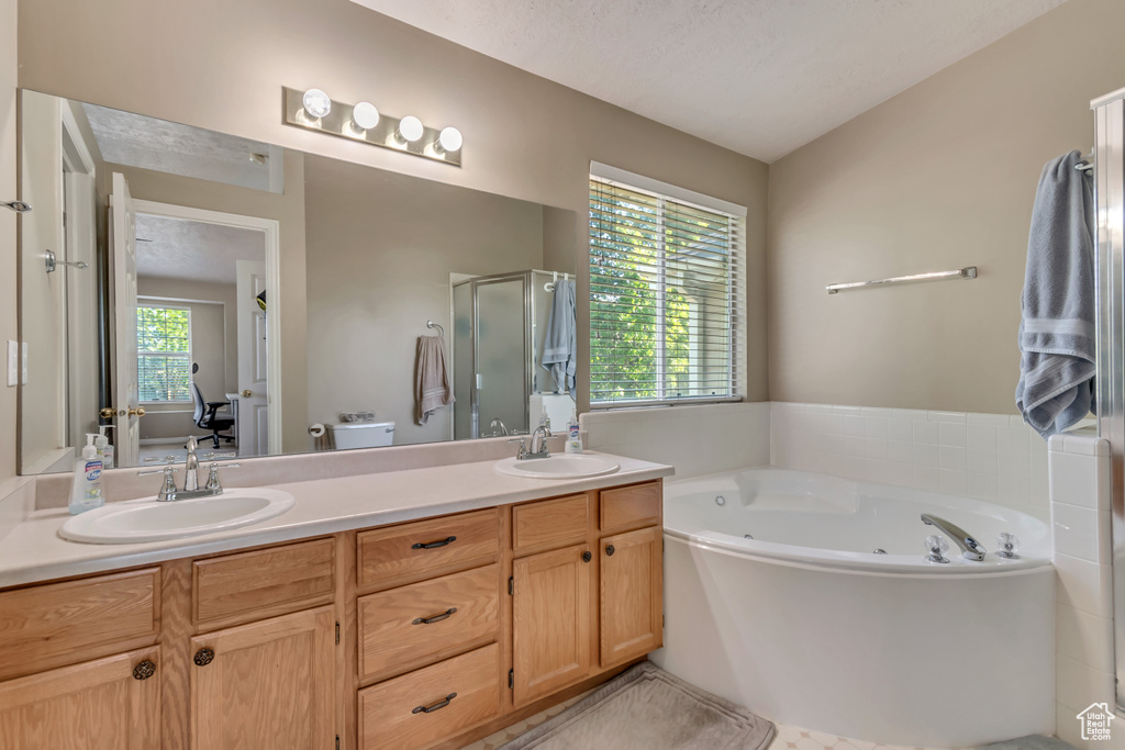 Bathroom with a stall shower, double vanity, and a whirlpool tub