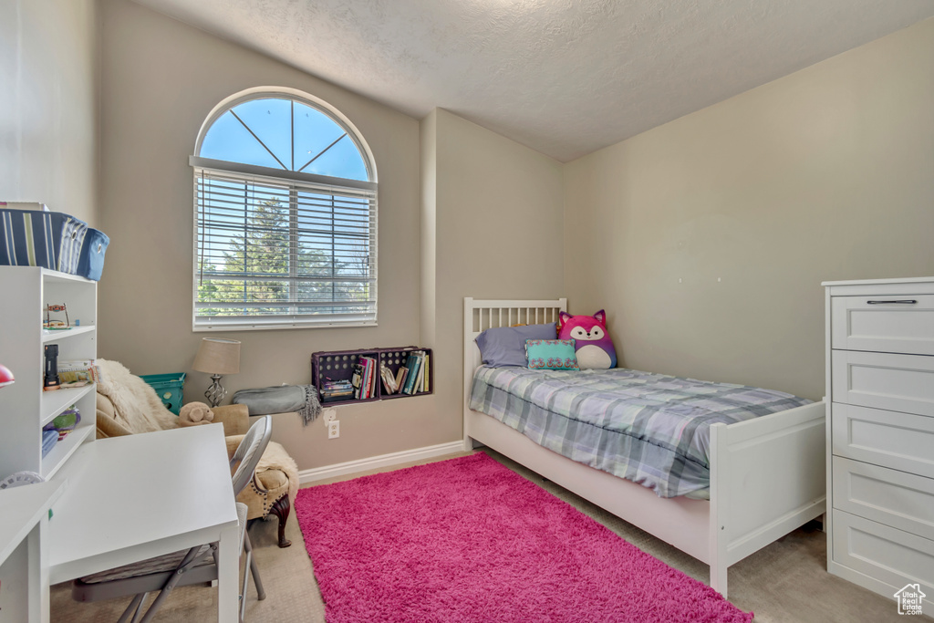 Carpeted bedroom featuring a textured ceiling and baseboards