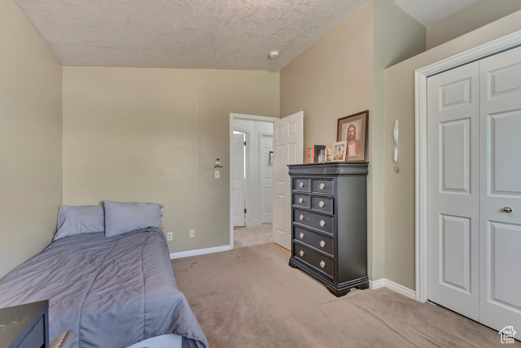 Bedroom with carpet floors, baseboards, and a textured ceiling