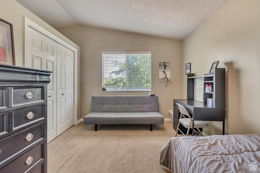 Bedroom featuring vaulted ceiling, light colored carpet, a closet, baseboards, and a textured ceiling