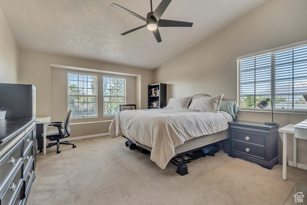 Bedroom featuring light colored carpet, vaulted ceiling, a desk, baseboards, and ceiling fan