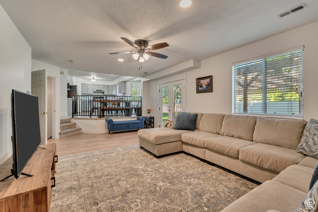 Living area with wood finished floors, a ceiling fan, stairs, recessed lighting, and french doors