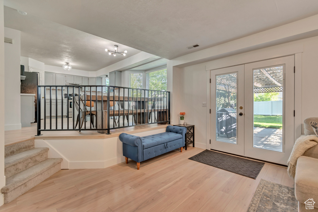 Entrance foyer with light wood-type flooring, french doors, a chandelier, and stairs