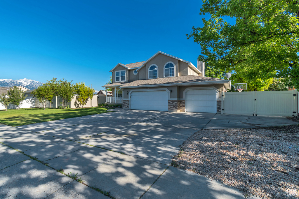 Traditional-style home featuring a gate, concrete driveway, stone siding, stucco siding, and a garage