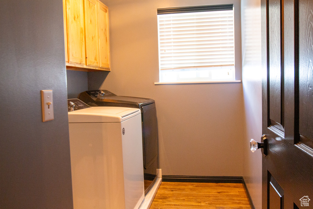 Laundry area with cabinet space, washing machine and dryer, light wood-type flooring, and baseboards