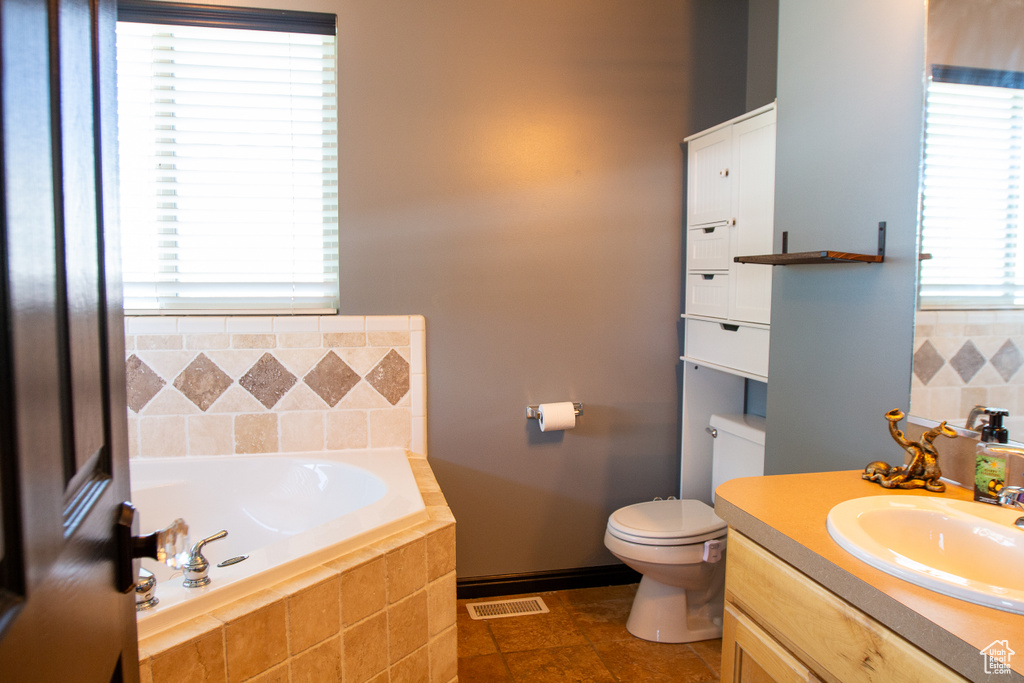 Full bath featuring a garden tub, toilet, and vanity
