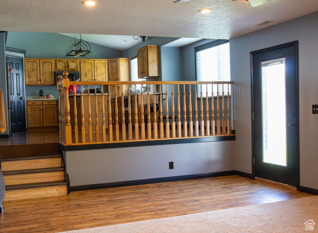 Kitchen with vaulted ceiling, wood finished floors, a textured ceiling, recessed lighting, and baseboards