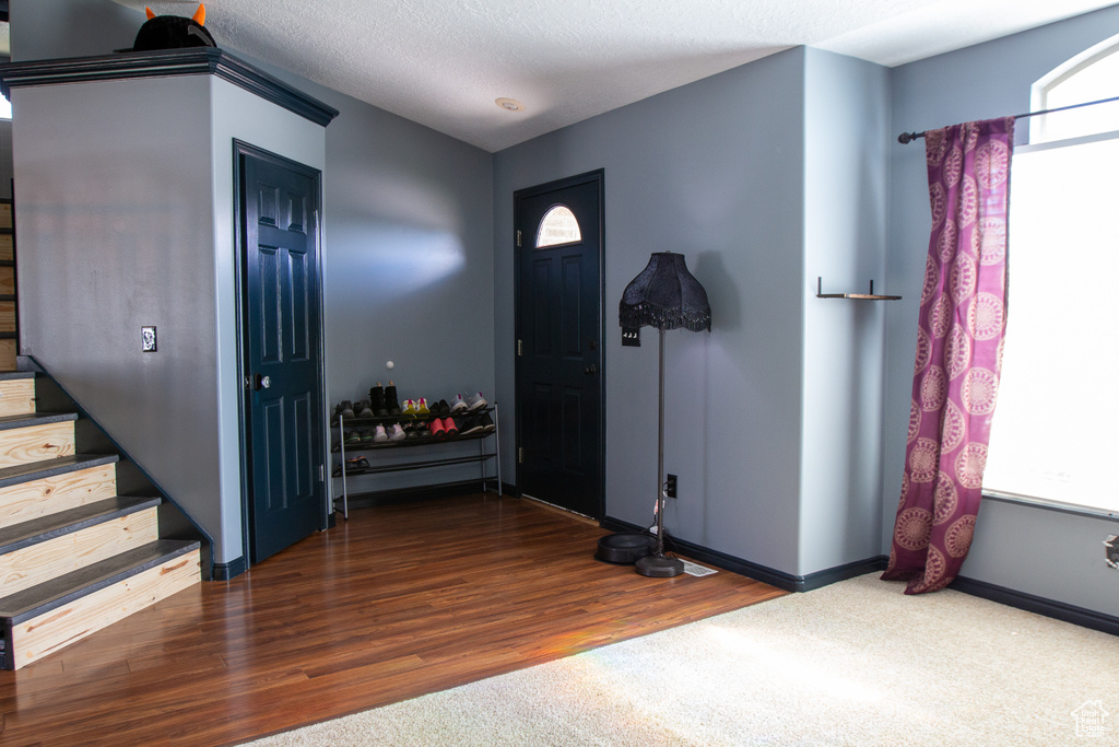 Entrance foyer with stairway, wood finished floors, baseboards, and a textured ceiling
