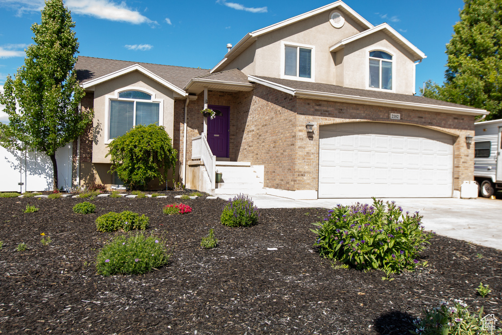 View of front of property featuring concrete driveway, stucco siding, an attached garage, and brick siding