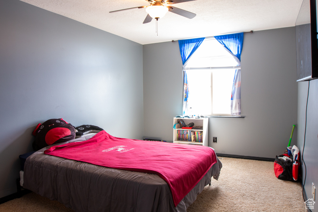Carpeted bedroom featuring multiple windows, a ceiling fan, and baseboards