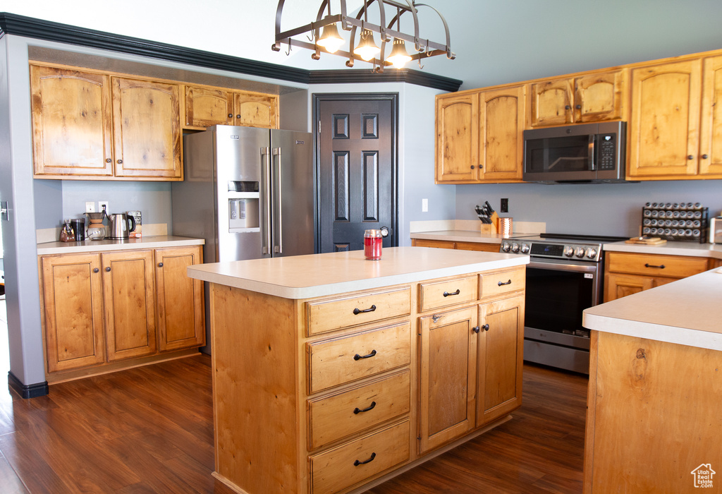 Kitchen with stainless steel appliances, dark wood finished floors, light countertops, a center island, and pendant lighting