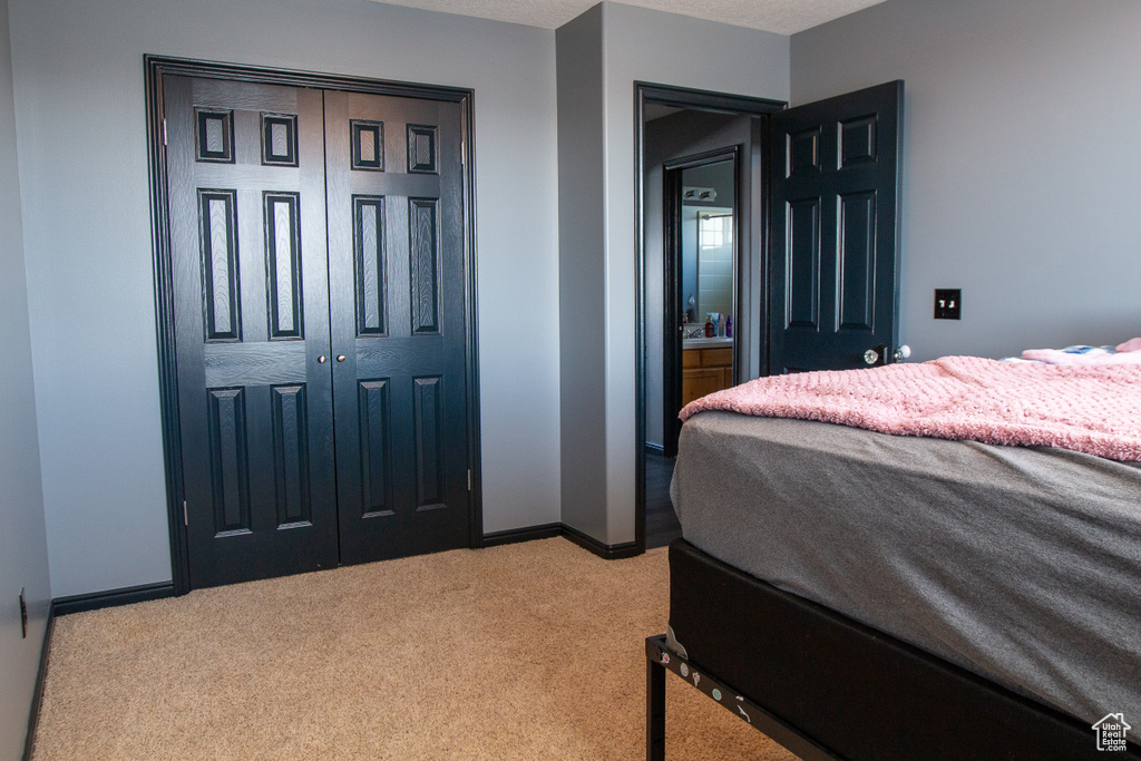 Bedroom featuring light carpet, baseboards, and a closet
