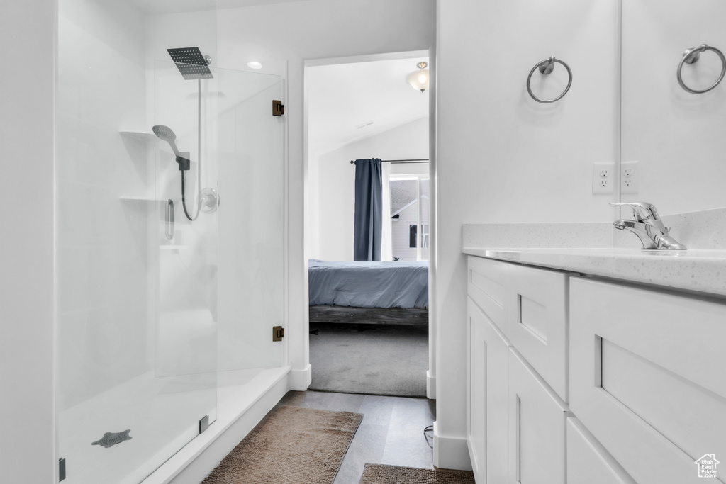 Bathroom featuring a shower stall, vanity, ensuite bath, and lofted ceiling
