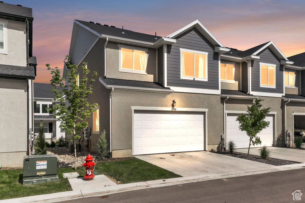 View of front of home with a garage, stucco siding, concrete driveway, and cooling unit