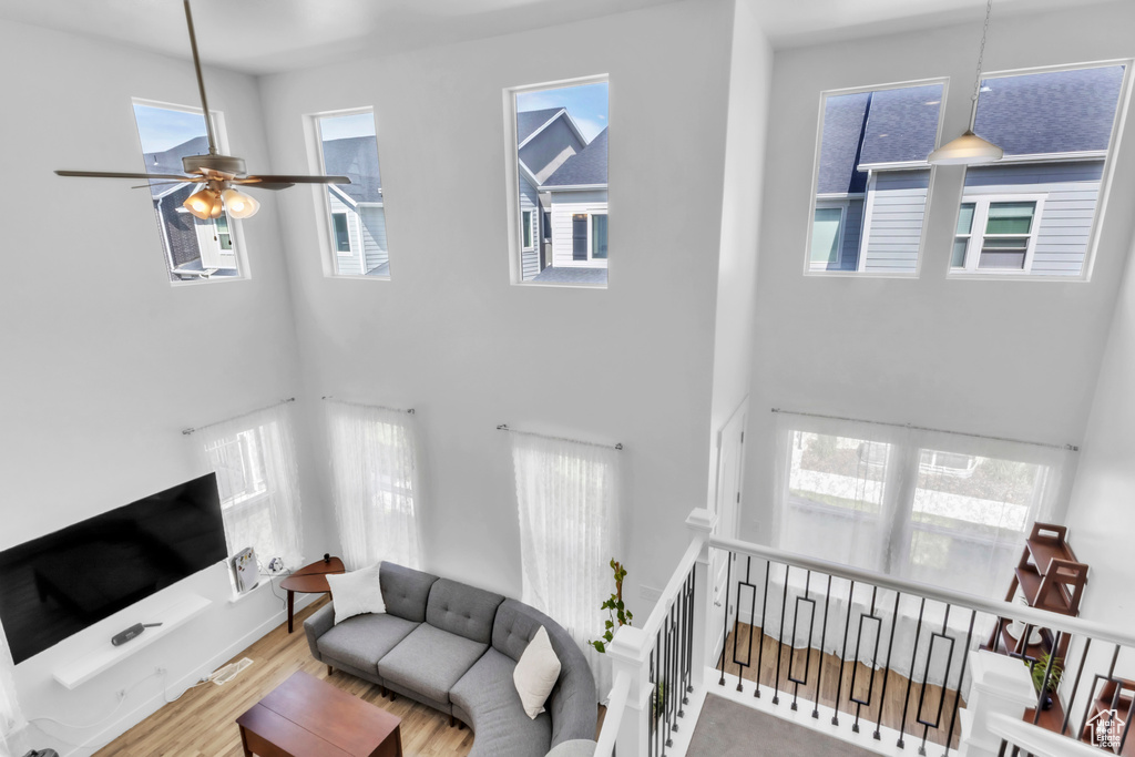 Living room with a high ceiling, a ceiling fan, and wood finished floors