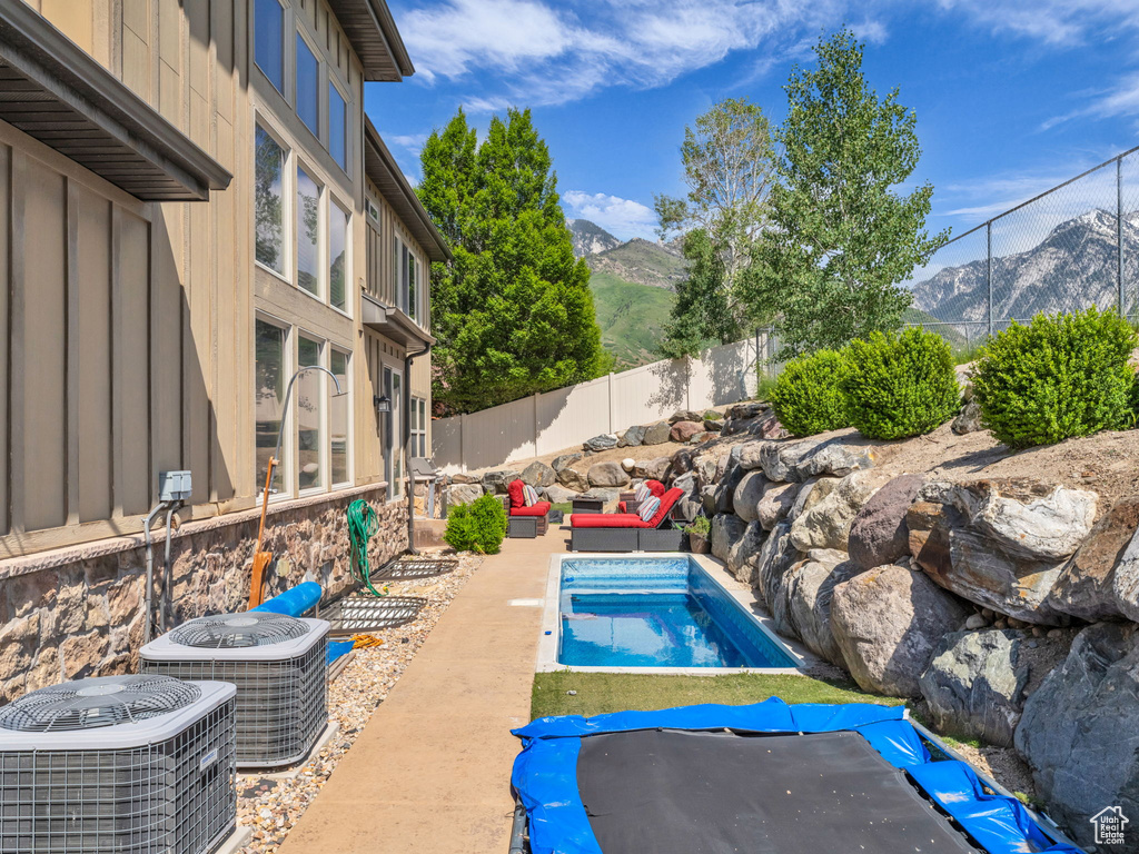 View of pool featuring central air condition unit, a mountain view, a fenced backyard, and an outdoor living space