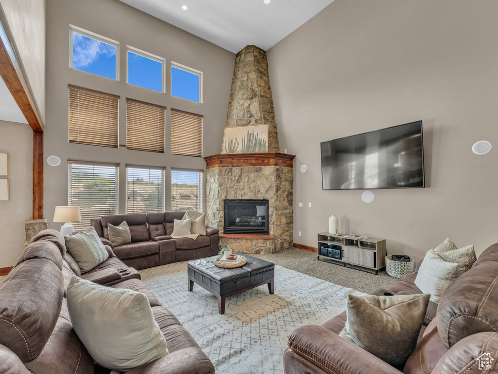 Living room featuring a high ceiling, baseboards, carpet flooring, a stone fireplace, and recessed lighting