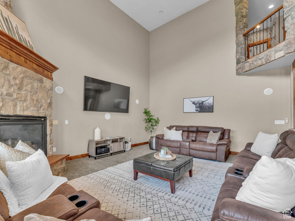 Living area with a towering ceiling, carpet flooring, baseboards, and a fireplace