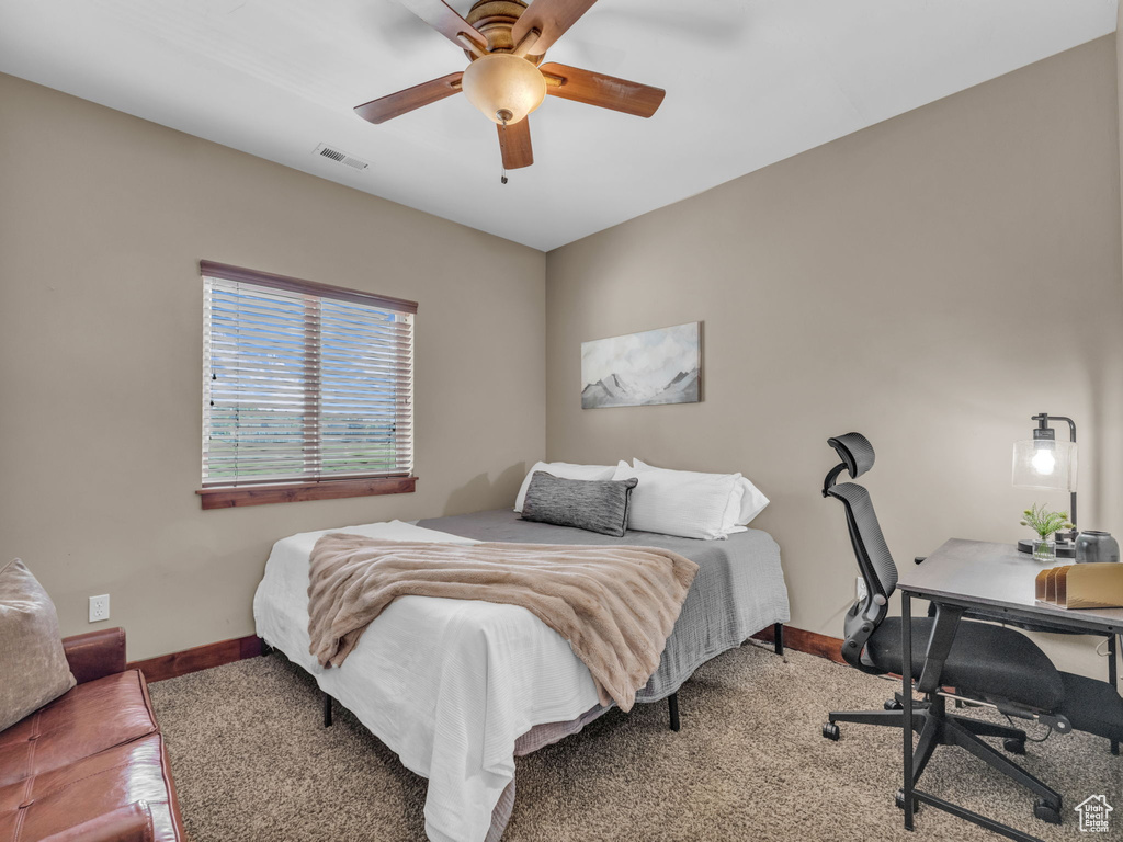 Carpeted bedroom with baseboards, an office area, and a ceiling fan