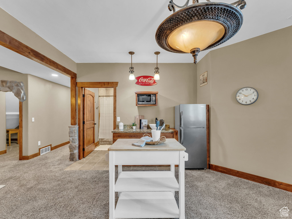 Kitchen with appliances with stainless steel finishes, light colored carpet, and baseboards