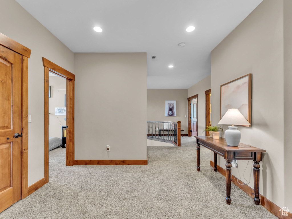 Hallway featuring carpet, baseboards, an upstairs landing, and recessed lighting