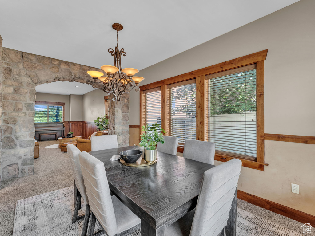 Dining space with wainscoting, a chandelier, and carpet