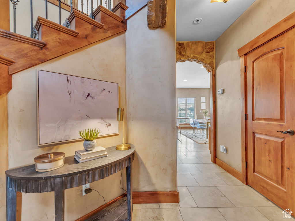Corridor featuring light tile patterned floors, baseboards, and arched walkways