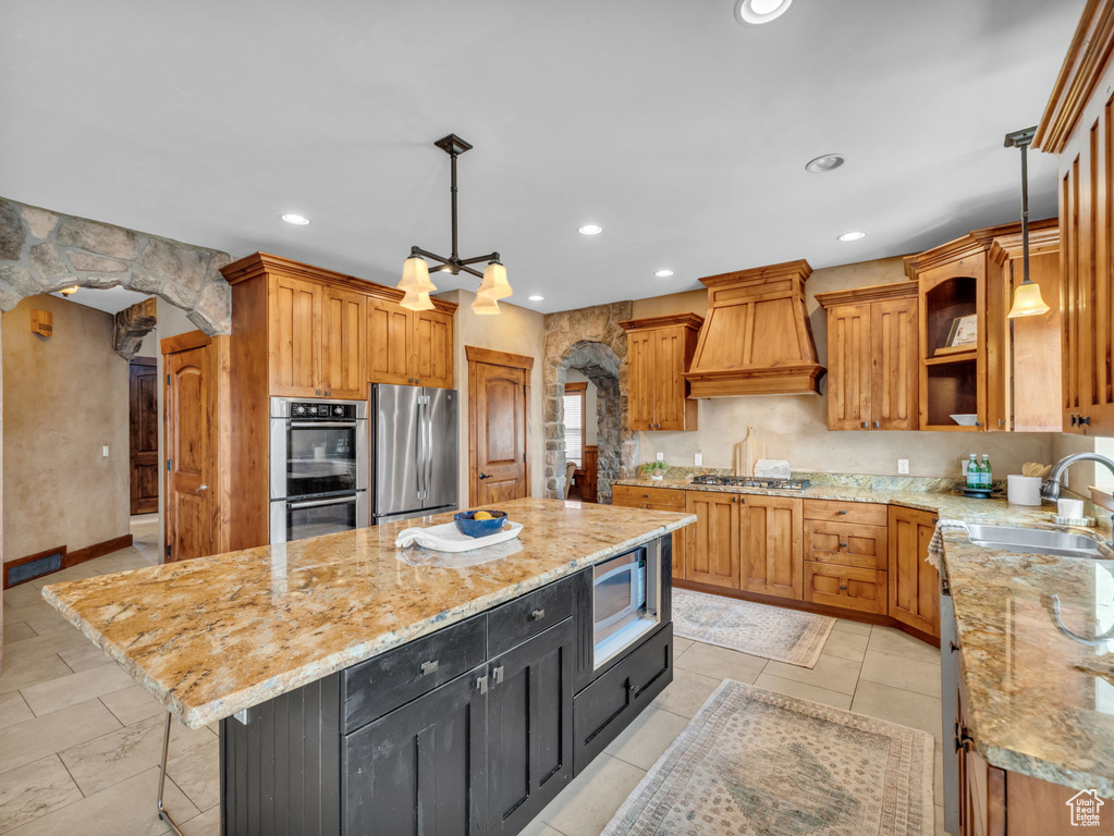Kitchen featuring stainless steel appliances, custom range hood, a sink, a center island, and open shelves
