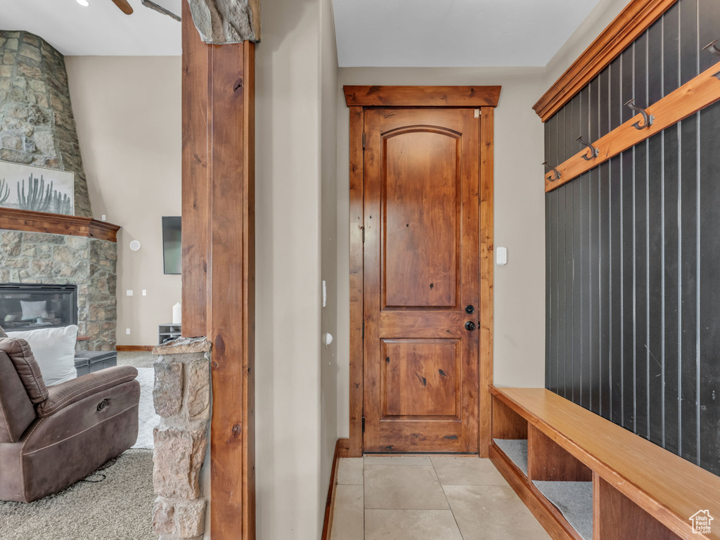 Mudroom with light tile patterned flooring, a stone fireplace, and baseboards